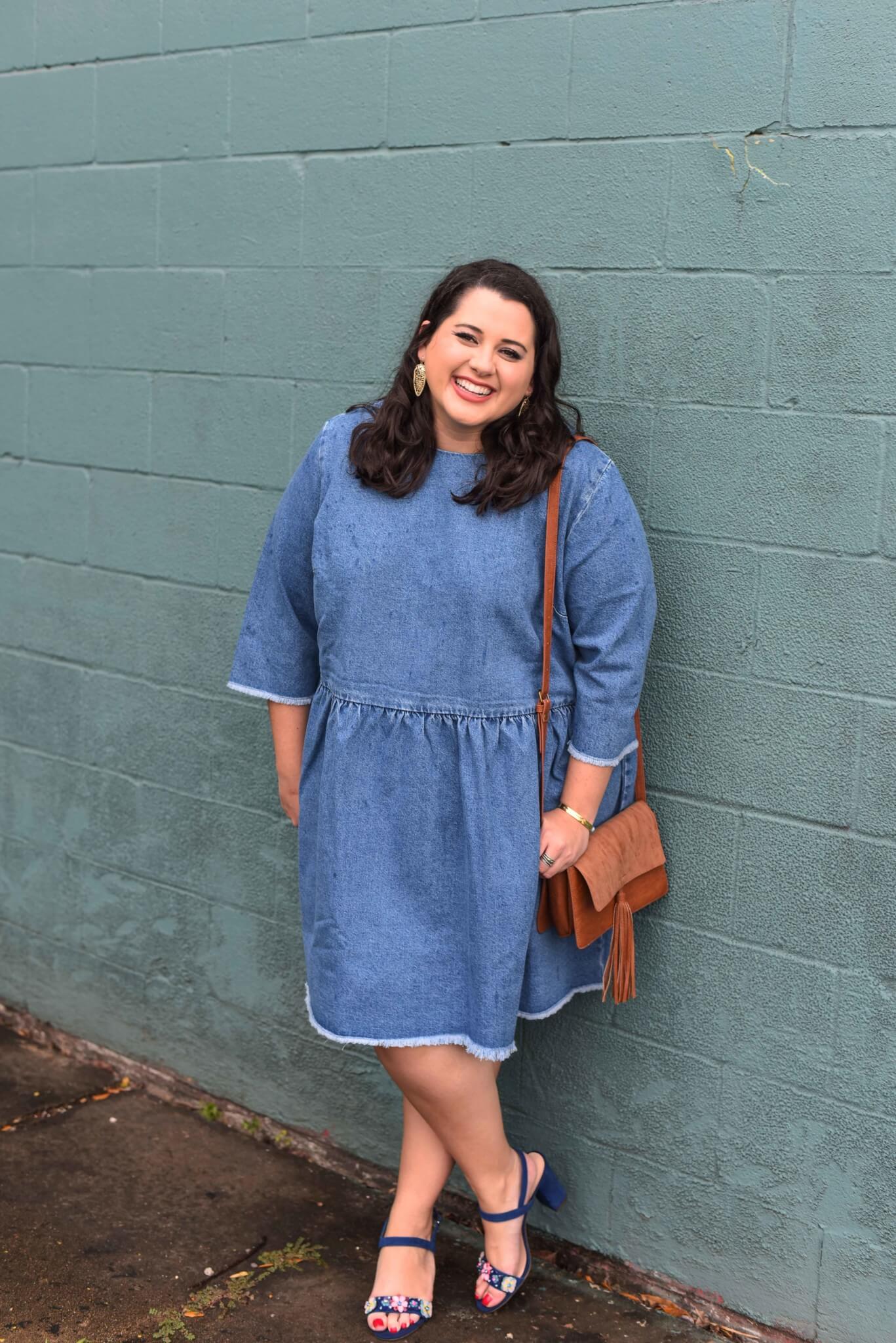 Spring style in a denim dress. Emily Bastedo, curvy style blogger from Something Gold, Something Blue features this comfortable and versatile dress perfect for running errands or a night on the town. She's currently ready to go to brunch with a statement heel, small clutch and bold earrings. Brunch style, spring style, plus size style, plus size fashion, floral