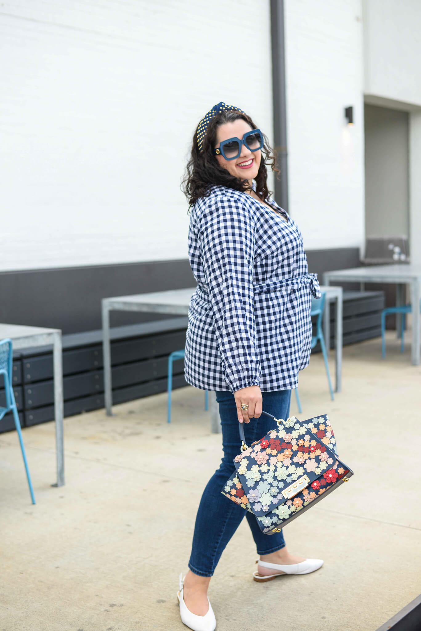 The perfect preppy fall transition outfit includes a navy and white plus size gingham top, skinny jeans and embellished headband